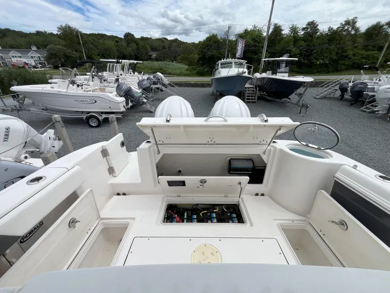 Slide: The Image of 2024 Robalo R302 Center Console boat interior with seating and table, docked near a garage. - 9