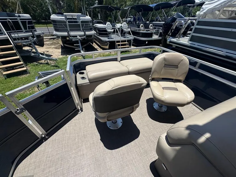 Slide: The Image of 2024 Sun Tracker Fishin' Barge 22 DLX interior with beige seating and cup holders. - 6