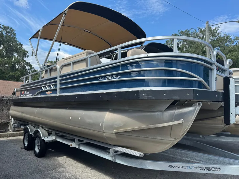 Slide: The Image of 2024 Sun Tracker Fishin' Barge 22 DLX pontoon boat on trailer, blue with canopy. - 8
