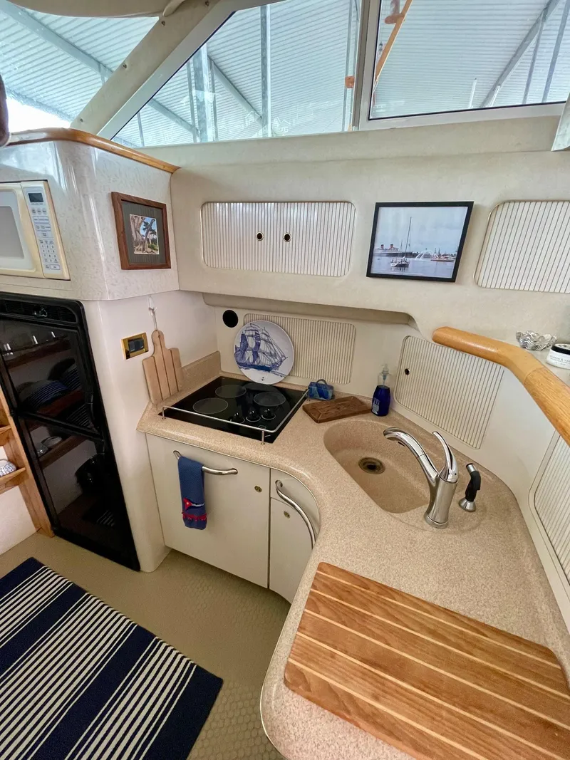 Slide: The Image of 1997 Sea Ray 400 Sedan Bridge kitchen with stove, sink, and wooden cutting board. - 13