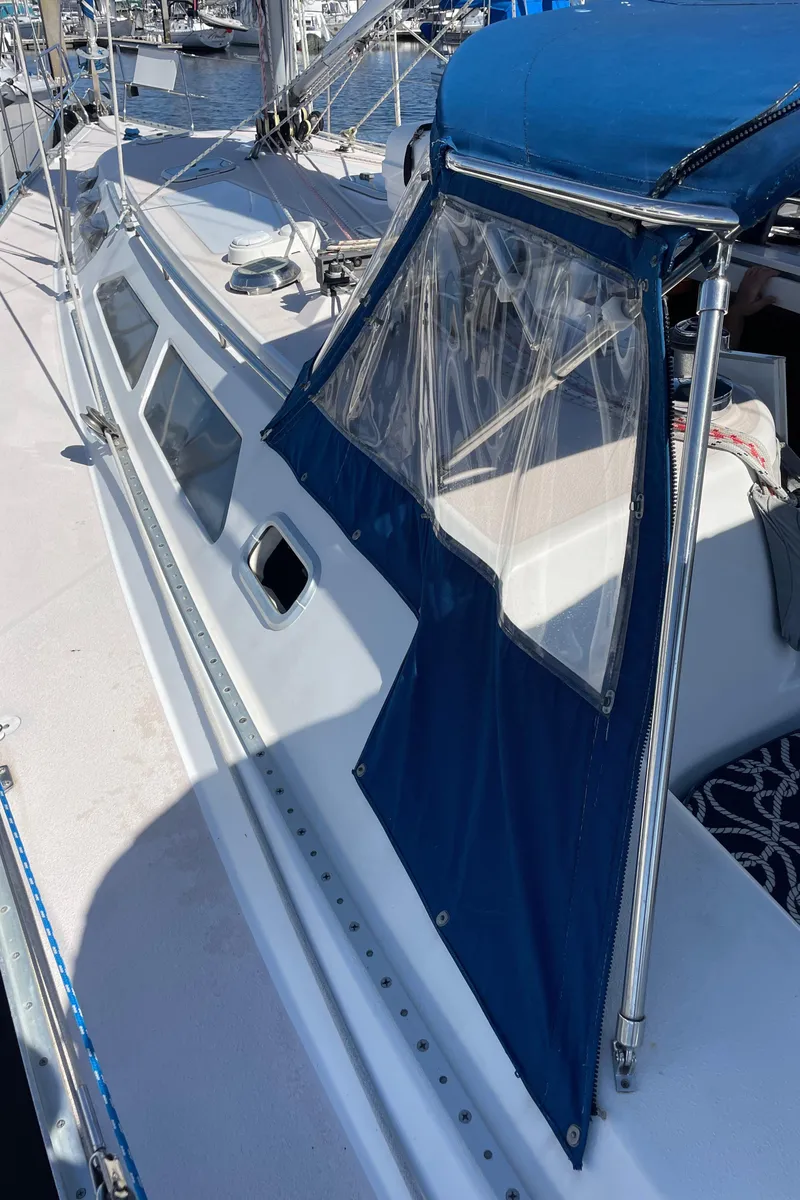Slide: The Image of 1998 Catalina 400 sailboat with blue canopy and clear windows, docked at marina. - 33