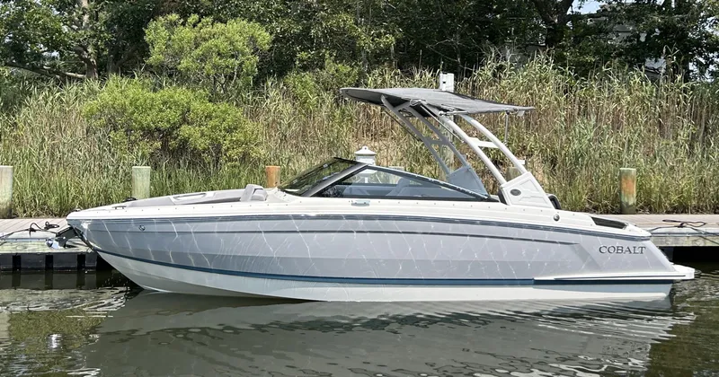Slide: The Image of 2026 Cobalt R4 boat docked on calm water, surrounded by lush greenery. - 1