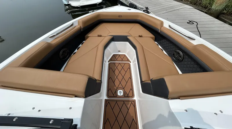 Slide: The Image of 2026 Cobalt R4 Outboard boat interior with tan seating and wood accents at a dock. - 15