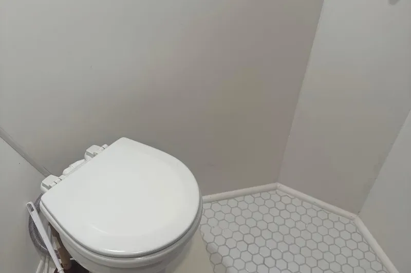 Slide: The Image of White toilet in a 1970 Hatteras 45 Convertible boat bathroom with hexagonal tile flooring. - 23