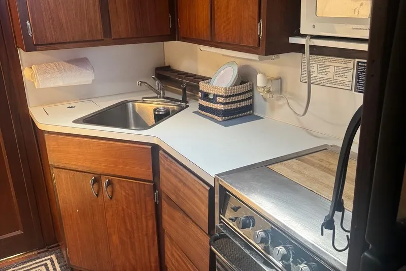 Slide: The Image of 1970 Hatteras 45 Convertible yacht kitchen with wooden cabinets, sink, and stove. - 28