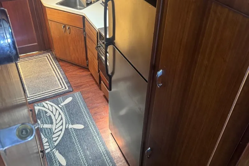 Slide: The Image of Interior of 1970 Hatteras 45 Convertible yacht kitchen with wood cabinets and nautical-themed rug. - 29