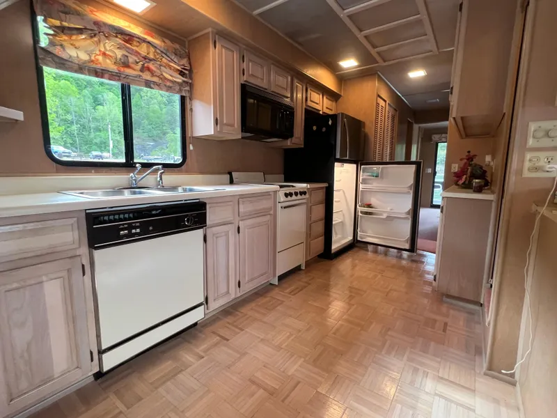 Slide: The Image of 1993 Sumerset houseboat kitchen with wood cabinets, open fridge, and scenic window view. - 10