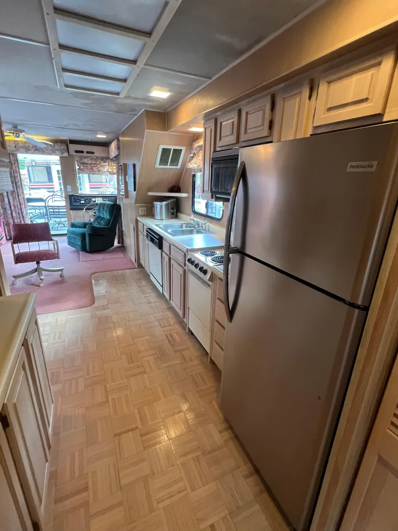 Slide: The Image of Interior of a 1993 Sumerset houseboat featuring a kitchen with appliances and seating area. - 11