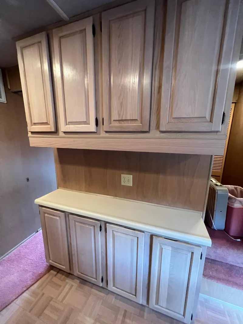 Slide: The Image of Wooden cabinets inside a 1993 Sumerset houseboat, featuring ample storage and a countertop. - 14