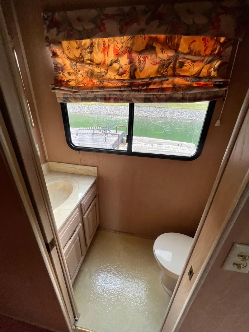 Slide: The Image of 1993 Sumerset houseboat bathroom with window, floral curtain, sink, and toilet. - 16