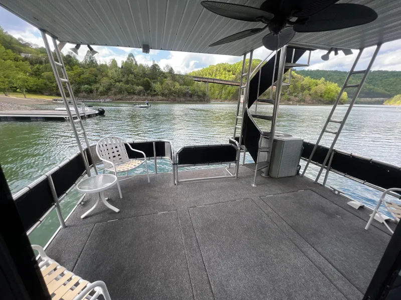 Slide: The Image of 1993 Sumerset houseboat deck with spiral staircase, overlooking serene lake and lush green hills. - 18