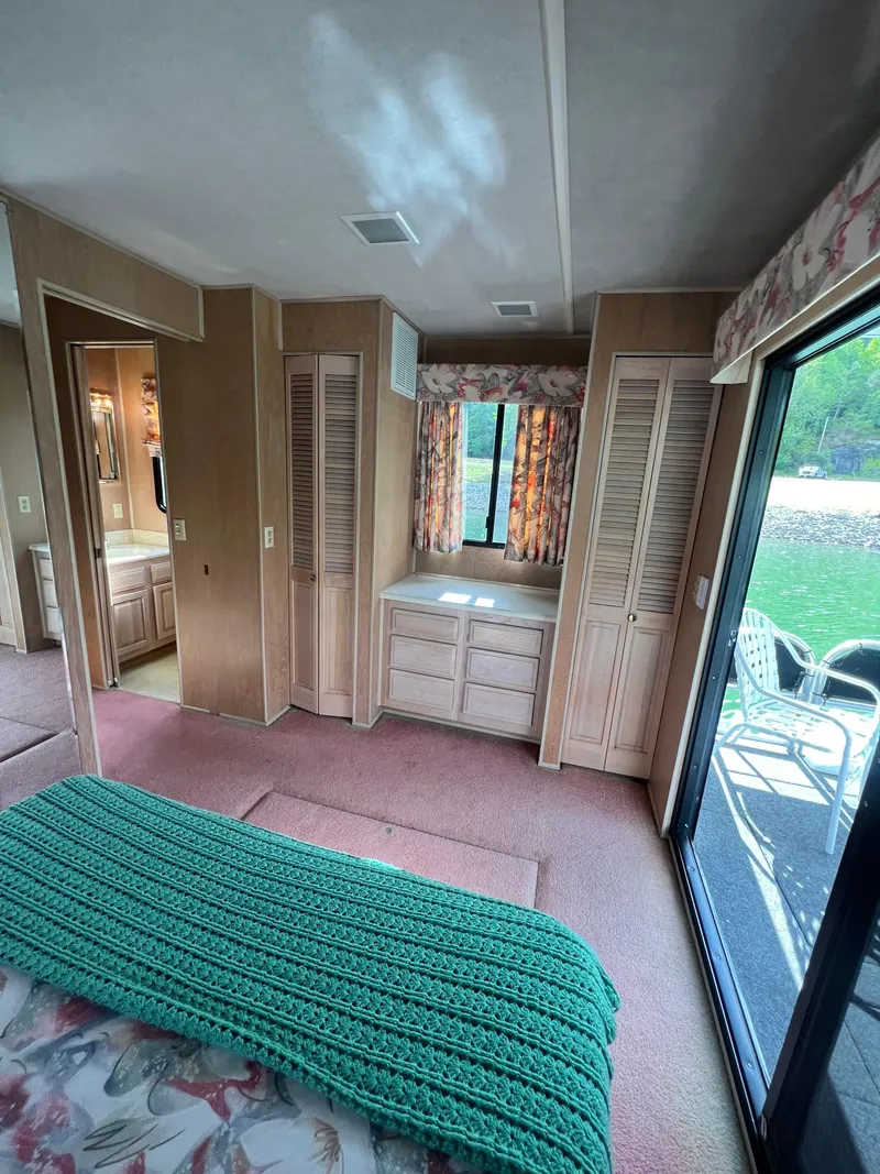 Slide: The Image of 1993 Sumerset houseboat interior with cozy bedroom, floral curtains, and outdoor view. - 24