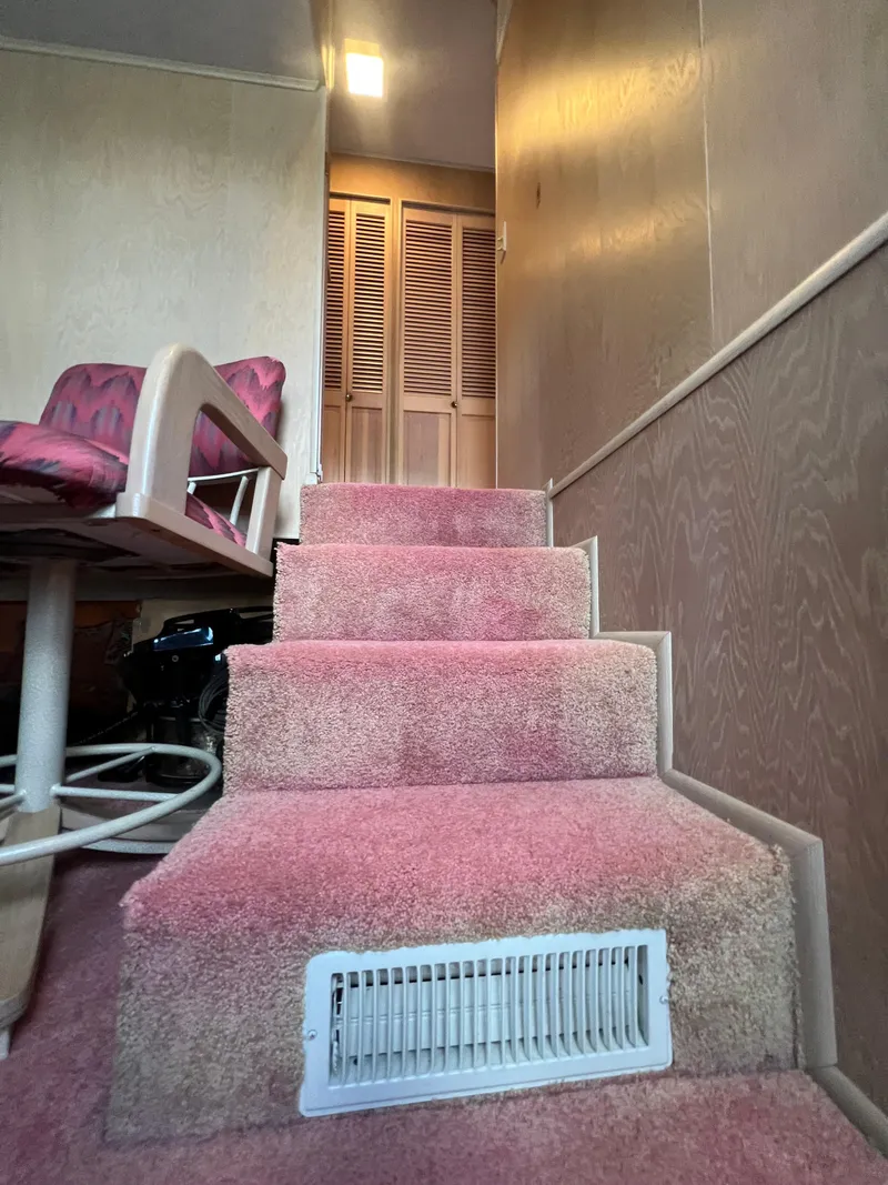 Slide: The Image of Interior of a 1993 Sumerset houseboat with pink carpeted stairs and wooden paneling. - 29