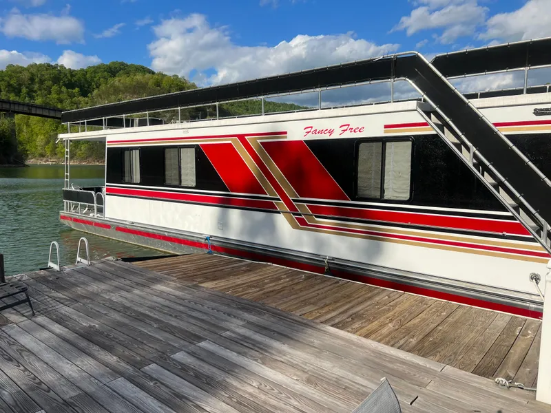 Slide: The Image of 1993 Sumerset houseboat docked on a lake, featuring red and white design. - 32
