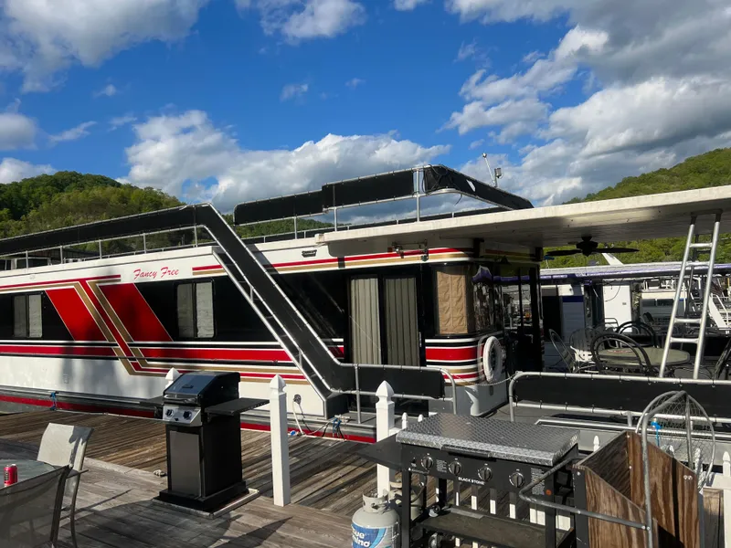 Slide: The Image of 1993 Sumerset houseboat with red and black accents docked under a blue sky. - 33