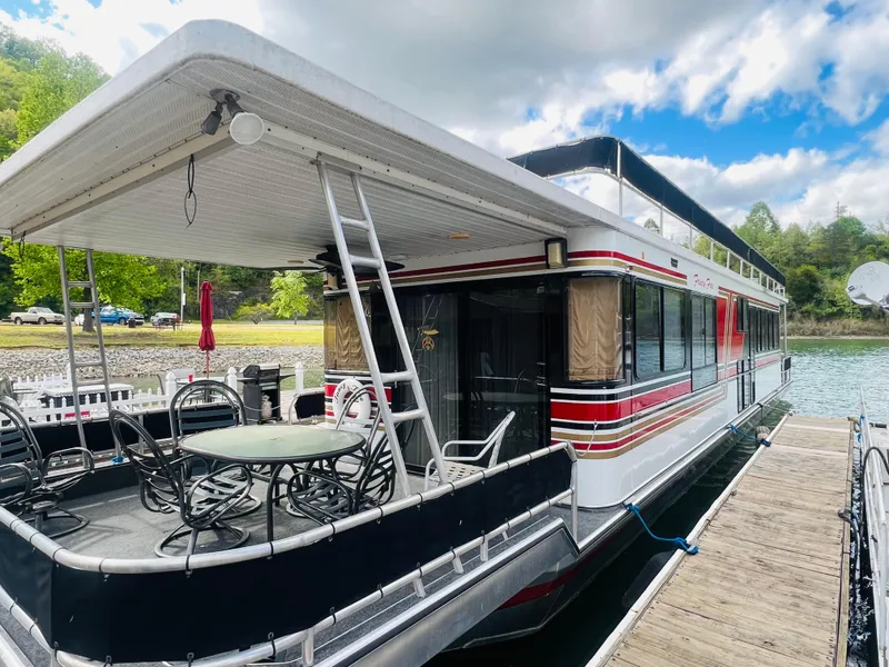 Slide: The Image of 1993 Sumerset houseboat docked, featuring outdoor seating and scenic lake view. - 8