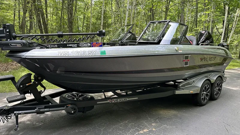 Slide: The Image of 2024 Vexus DVX20 boat on trailer in wooded area. - 2