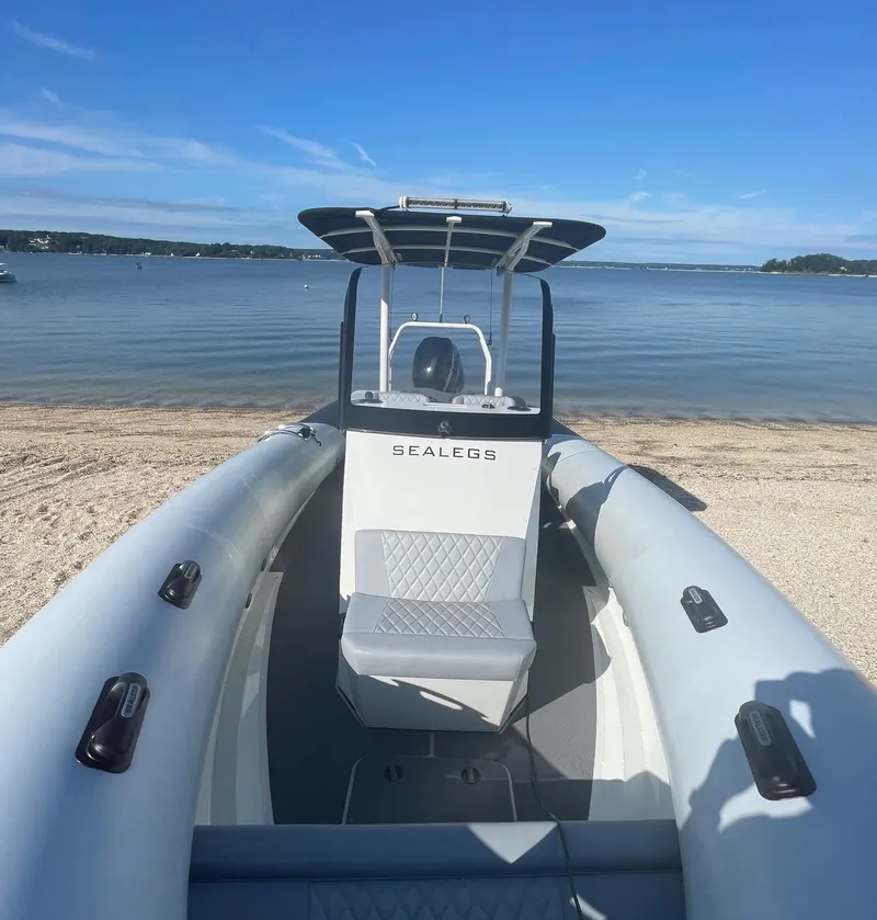 Slide: The Image of 2023 Sealegs 9M RIB boat on sandy beach with clear blue sky and calm water. - 2