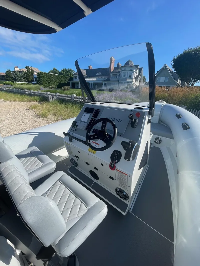 Slide: The Image of 2023 Sealegs 9M RIB boat interior with steering console, seats, and scenic background. - 4