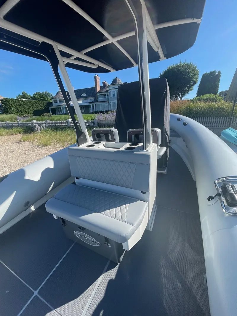 Slide: The Image of 2023 Sealegs 9M RIB boat interior with seating and canopy, near a house. - 5