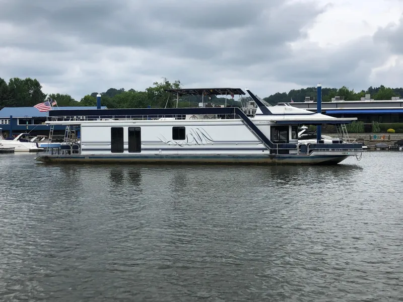 Slide: The Image of 1997 Sumerset 75' X 16' houseboat on a calm lake under cloudy skies. - 1