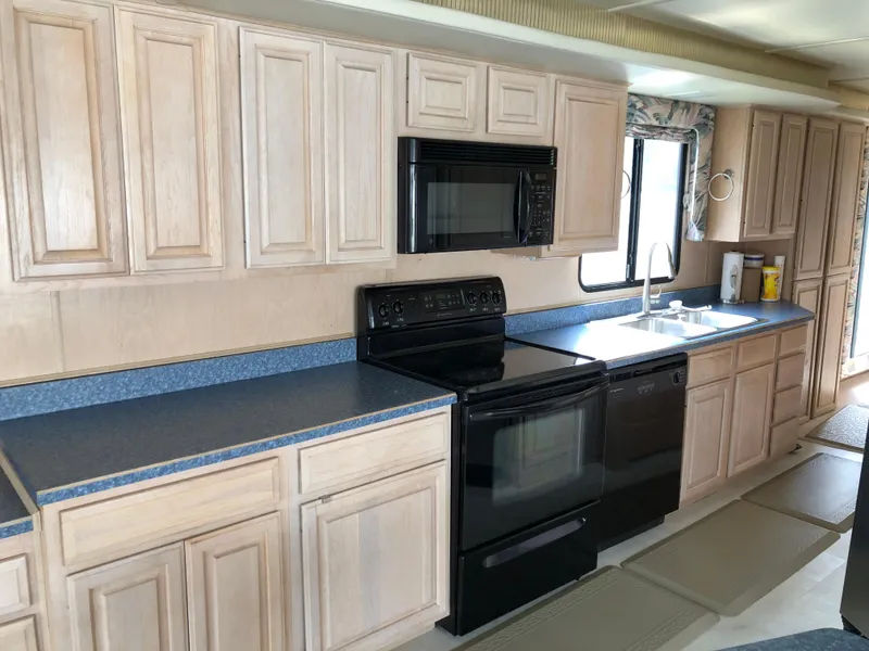 Slide: The Image of Kitchen interior of a 1997 Sumerset 75' X 16' houseboat with wooden cabinets and modern appliances. - 10
