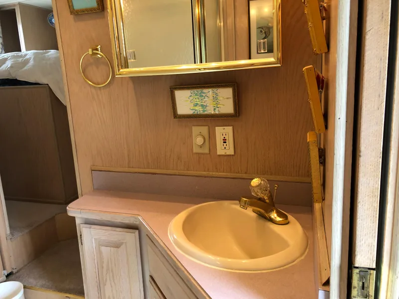 Slide: The Image of Bathroom vanity in a 1997 Sumerset 75' X 16' houseboat, featuring a sink and mirror. - 15