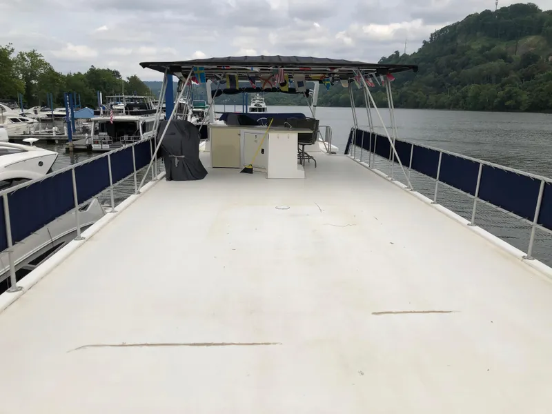 Slide: The Image of 1997 Sumerset 75' X 16' houseboat deck with canopy, docked by a scenic river. - 20