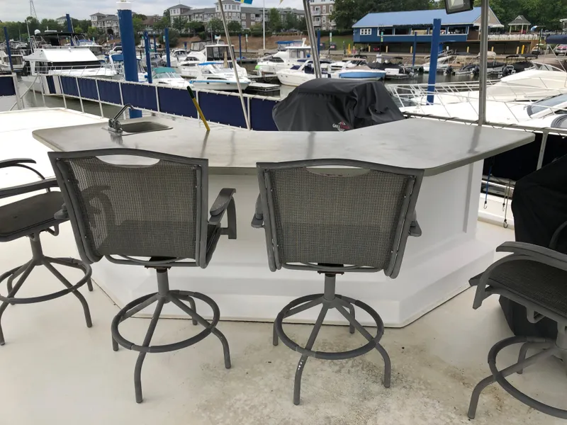 Slide: The Image of Outdoor bar area on a 1997 Sumerset 75' X 16' houseboat, featuring swivel chairs and marina view. - 22