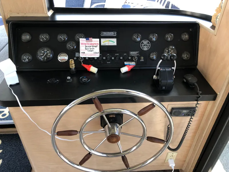 Slide: The Image of Control panel of a 1997 Sumerset 75' X 16' houseboat with steering wheel and gauges. - 27