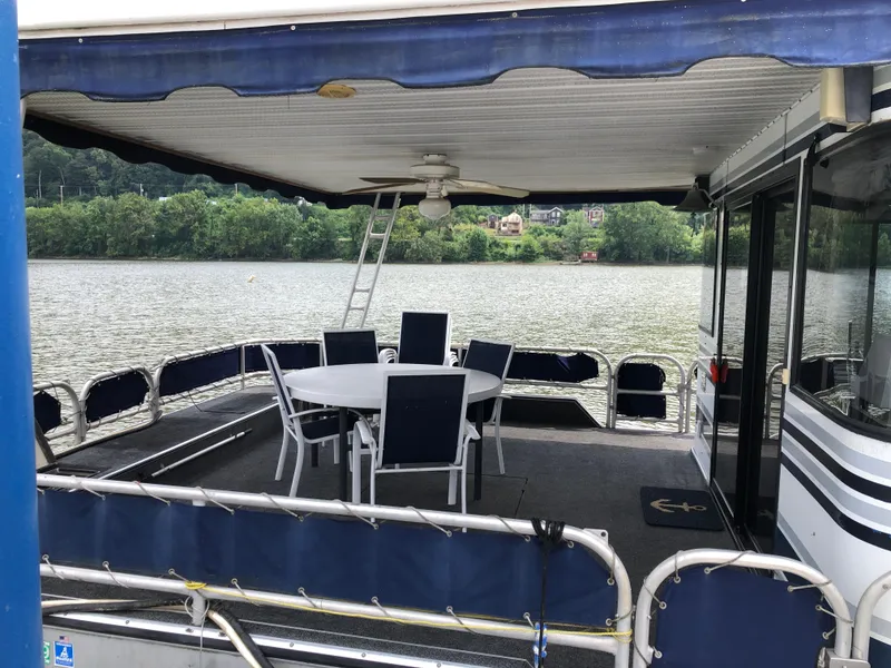 Slide: The Image of 1997 Sumerset 75' X 16' houseboat with outdoor seating on a scenic lake. - 3