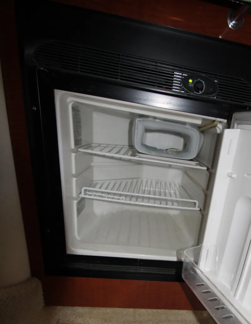 Slide: The Image of Open refrigerator inside a 2003 Sea Ray 320 Sundancer boat, showing empty shelves. - 12
