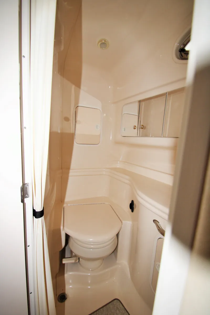 Slide: The Image of 2003 Sea Ray 320 Sundancer bathroom interior with compact toilet and storage compartments. - 13