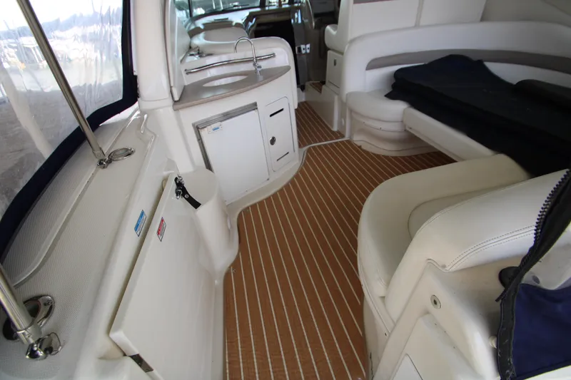 Slide: The Image of 2003 Sea Ray 320 Sundancer interior with seating, kitchenette, and wood-patterned flooring. - 26