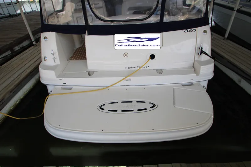 Slide: The Image of 2003 Sea Ray 320 Sundancer docked, rear view with swim platform and boat sales branding. - 5