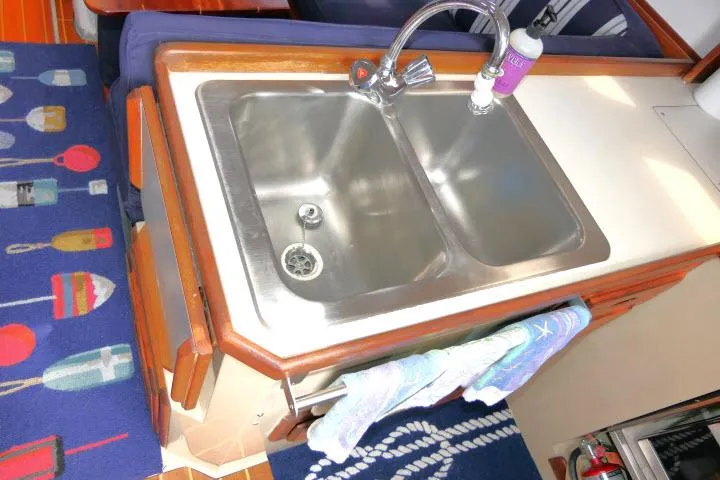 Slide: The Image of 1988 Catalina 34 yacht kitchen sink with faucet, colorful rug, and towel. - 17