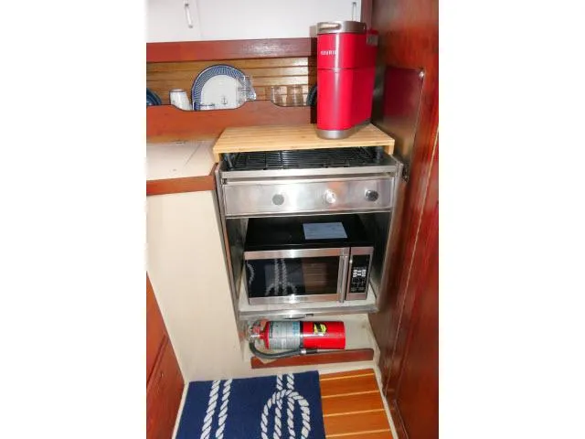 Slide: The Image of Compact kitchen area in a 1988 Catalina 34 sailboat with stove, microwave, and fire extinguisher. - 19
