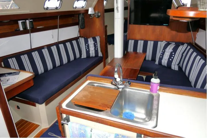 Slide: The Image of Interior of a 1988 Catalina 34 sailboat with cozy seating and a compact kitchen area. - 2