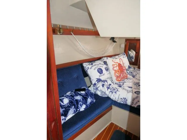 Slide: The Image of Cozy cabin interior of 1988 Catalina 34 sailboat with nautical-themed bedding and wooden accents. - 34