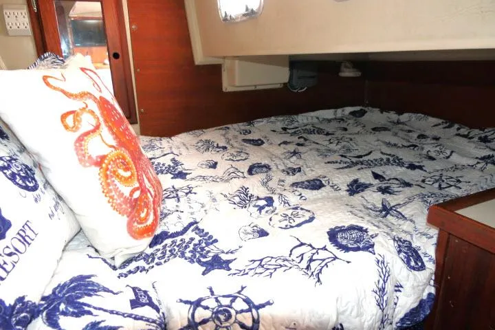 Slide: The Image of Cozy cabin bed in 1988 Catalina 34 sailboat with nautical-themed bedding and pillows. - 36