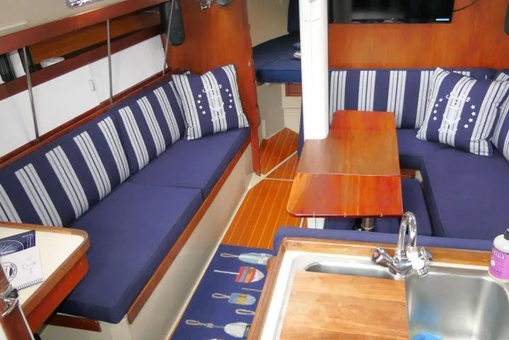 Slide: The Image of Interior of 1988 Catalina 34 sailboat with blue-striped seating and wooden table. - 4