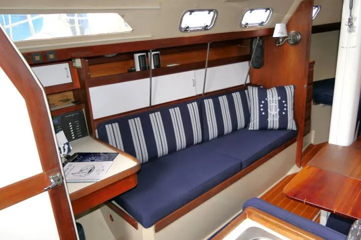 Slide: The Image of Interior of a 1988 Catalina 34 sailboat with blue-striped seating and wooden accents. - 5
