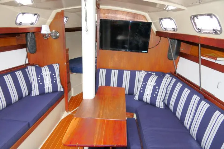 Slide: The Image of Interior of 1988 Catalina 34 sailboat with striped cushions and mounted TV. - 6