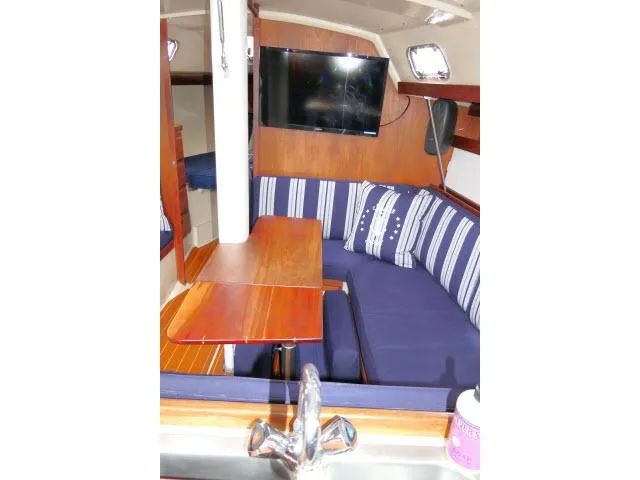 Slide: The Image of Interior of 1988 Catalina 34 sailboat with blue seating, wooden table, and mounted TV. - 7