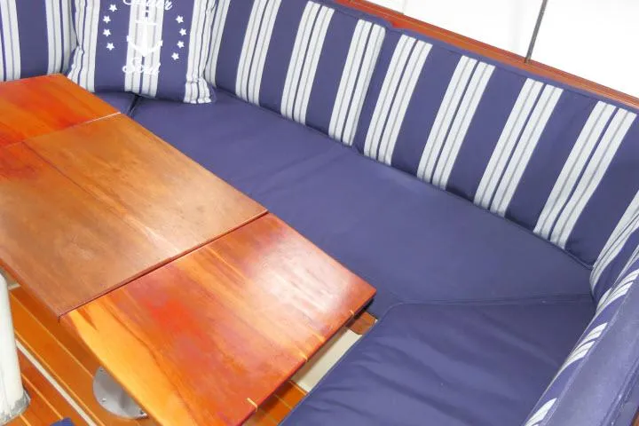 Slide: The Image of Cozy seating area on 1988 Catalina 34 sailboat with striped cushions and wooden table. - 9