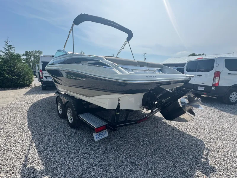 Slide: The Image of 2014 Crownline 235 SS boat on trailer, parked on gravel, with vehicles in background. - 4