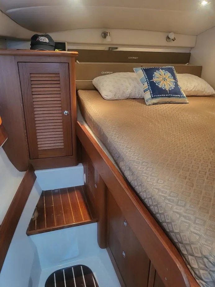 Slide: The Image of Cozy cabin interior of 2005 Glacier Bay 3480 Ocean Runner with wooden accents and bedding. - 13