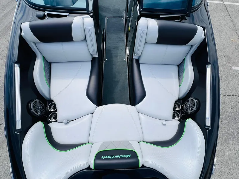 Slide: The Image of 2015 MasterCraft X25 boat interior with white and black seating, green accents, and cup holders. - 14