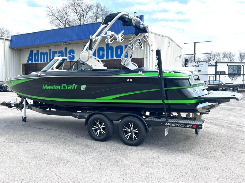 Slide: The Image of 2015 MasterCraft X25 boat with green accents on a trailer, parked outside a building. - 3