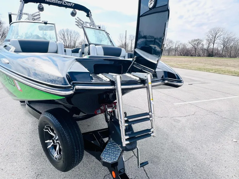 Slide: The Image of 2015 MasterCraft X25 boat with ladder, parked on pavement, showcasing sleek design and features. - 46